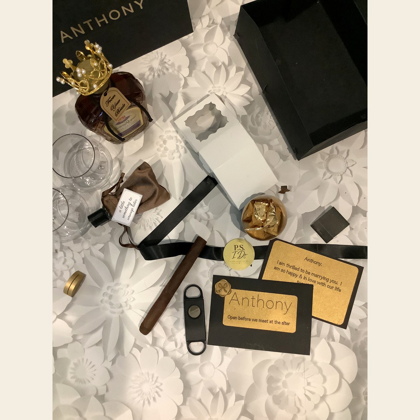 Flat lay of keepsake details including a cigar, cutter, cologne pouch, gold truffles, and personalized cards