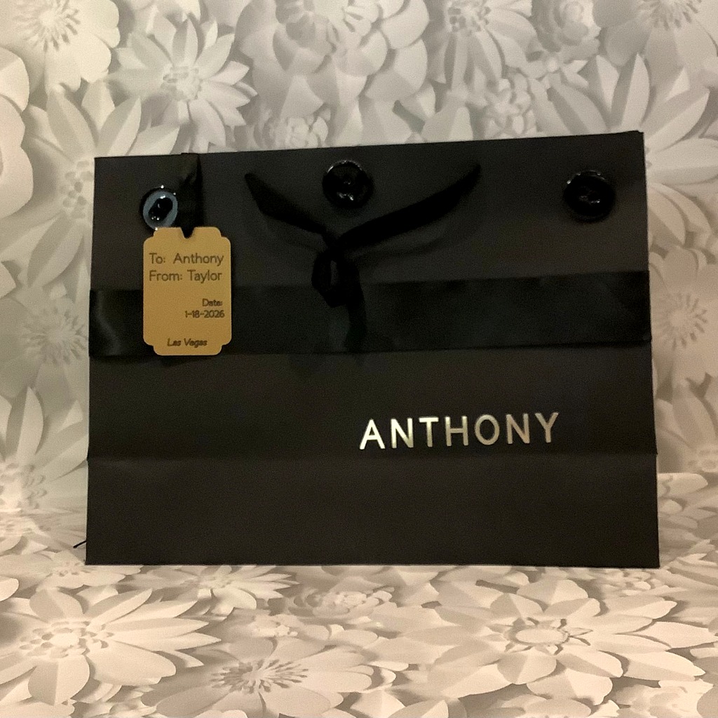 Black P.S. I Do gift bag personalized in gold with a ribbon and custom To/From gift tag