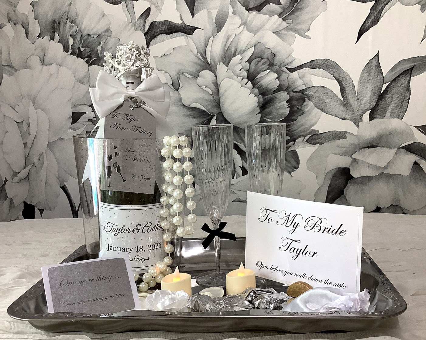 Silver bridal tray with personalized champagne bottle, flutes, pearls, candles, chocolates, and 'To My Bride' letter